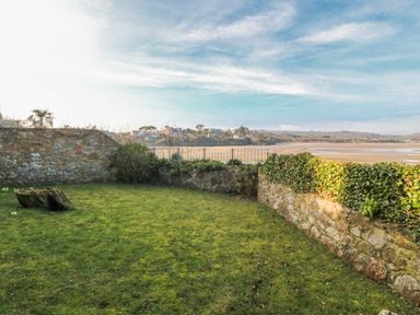A garden with stone walls and grass at Gilfach Goed Abersoch