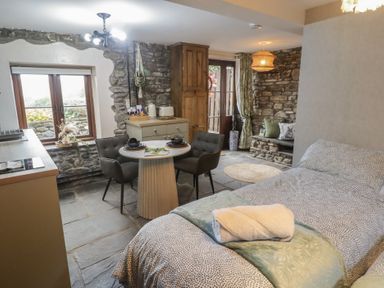 A bedroom with a bed, table, chairs and a window at Gwyn Studio in Aberdare