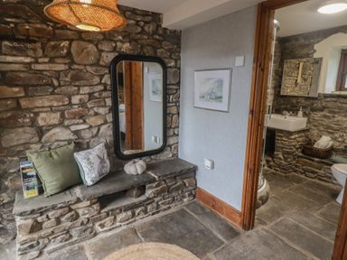 A bathroom with a mirror, bench, and a sink at Gwyn Studio in Aberdare