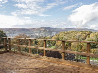 A view from a wooden deck overlooking mountains and trees at Gwyn Studio in Aberdare