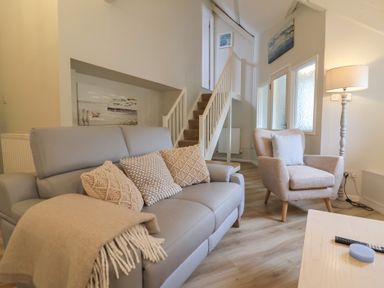 A living room with a sofa and staircase at Round Barn in Ilfracombe