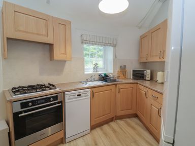 A kitchen with cabinets, sink, and oven at Round Barn in Ilfracombe