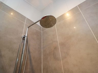 A shower head with tiles in the bathroom at 5 Waterside Wood Troutbeck Bridge
