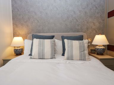 A bedroom with a bed, pillows, and lamps at 5 Waterside Wood Troutbeck Bridge