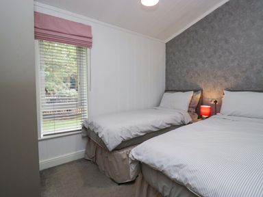 A bedroom with two beds and a window at 5 Waterside Wood in Troutbeck Bridge