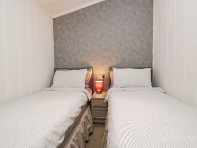 A bedroom with two single beds and a lamp at 5 Waterside Wood Troutbeck Bridge