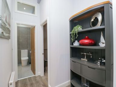 A hallway with a shelf and a view of a bathroom at 5 Waterside Wood Troutbeck Bridge