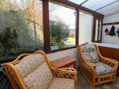 A conservatory with seating and a table at Bryncyn in Newport, Pembrokeshire