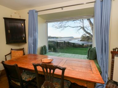 A dining room with a table and chairs overlooking a window at Bryncyn in Newport, Pembrokeshire