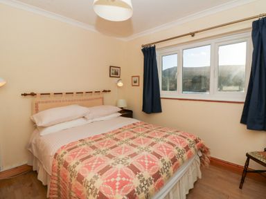 A bedroom featuring a bed with a patterned blanket at Bryncyn in Newport, Pembrokeshire