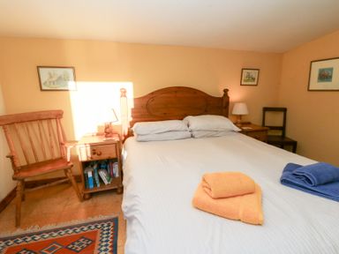 A bedroom with a bed, nightstand, and chair at Bryncyn in Newport, Pembrokeshire
