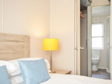 A bedroom with a lamp and connected bathroom at 2 Summerleaze, Bude