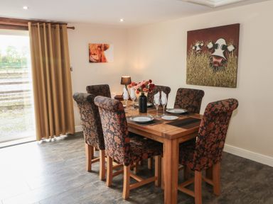 A dining room with a wooden table and floral chairs at Pompian Lodge Leyland