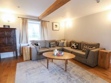 A living room with a sofa, coffee table and wooden cabinet at Secret Garden Cottage Ciliau Aeron near Aberaeron