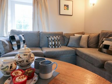 A living room with a sofa and tea set at Secret Garden Cottage, Ciliau Aeron near Aberaeron