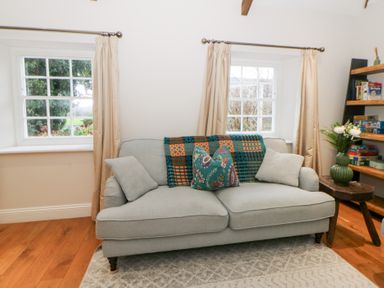 A living room with a sofa and shelves at Secret Garden Cottage in Ciliau Aeron near Aberaeron