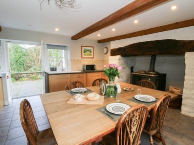 A kitchen with a dining table and flowers at Secret Garden Cottage, Ciliau Aeron near Aberaeron