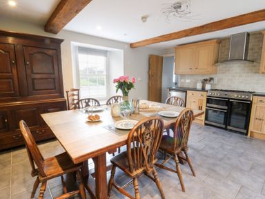 A dining room with a wooden table and sideboard at Secret Garden Cottage, Ciliau Aeron near Aberaeron