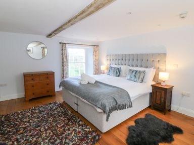 A bedroom with a bed and a dresser at Secret Garden Cottage in Ciliau Aeron near Aberaeron