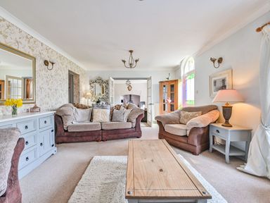 A living room with a sofa, coffee table, and lamp at The Old Farm House near Pelynt