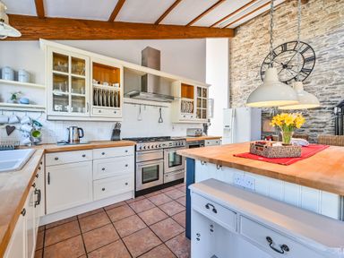 A kitchen with cabinets, a stove, and a refrigerator at The Old Farm House near Pelynt
