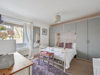 A bedroom with a bed, wardrobe, and table at The Old Farm House near Pelynt