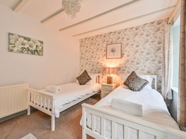 A bedroom with two beds and a lamp at The Old Farm House near Pelynt