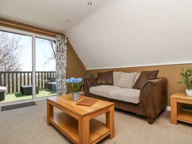 A living room with a sofa, coffee table, and glass door at Valley Lodge 61 Callington