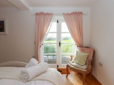 A bedroom with a bed and a chair at Hilldown Granary near Bow