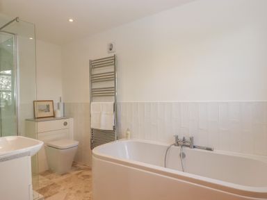 A bathroom with a bathtub, shower, toilet, and sink at Hilldown Granary near Bow