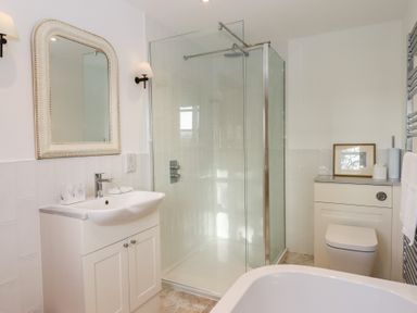 A bathroom with a shower, sink, and toilet at Hilldown Granary near Bow