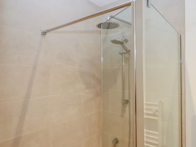 A shower with glass enclosure and towel radiator at Hilldown Cott near Bow