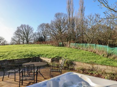 A garden with chairs and a table near a hot tub at Hilldown Cott near Bow