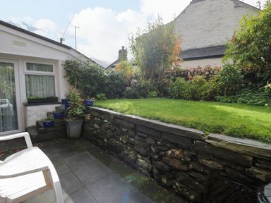 A garden with grass and flower pots at Noddfa in Penmachno