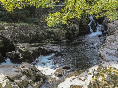 A river flowing over rocks with a waterfall at Noddfa Penmachno