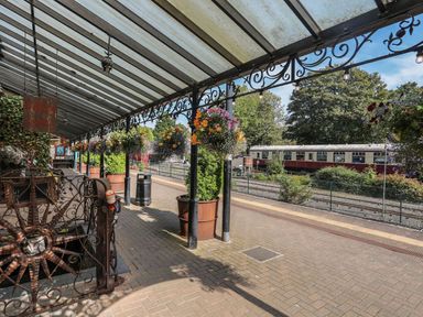 An outdoor train station platform with planters and a train at Noddfa Penmachno