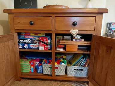 A wooden cabinet with board games and toys at Noddfa in Penmachno