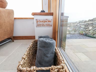 A basket with towels and a sign near a window at 2 Trem Y Mor Llanfwrog near Llanfachraeth