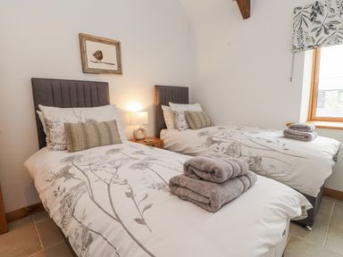A bedroom with two beds and a lamp at 2 Trem Y Mor Llanfwrog near Llanfachraeth