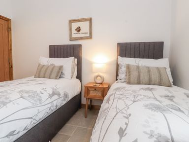 A bedroom with two beds and a nightstand at 2 Trem Y Mor Llanfwrog near Llanfachraeth