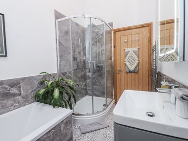A bathroom with a shower, bathtub, and sink at 2 Trem Y Mor in Llanfwrog near Llanfachraeth