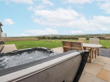 An outdoor area with a hot tub and seating at 2 Trem Y Mor Llanfwrog near Llanfachraeth
