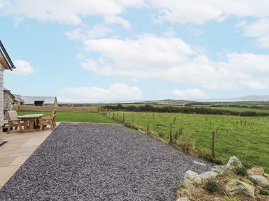 An outdoor area with a table and chairs at 2 Trem Y Mor Llanfwrog near Llanfachraeth