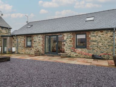 An outdoor view of a stone building with a patio at 2 Trem Y Mor Llanfwrog near Llanfachraeth
