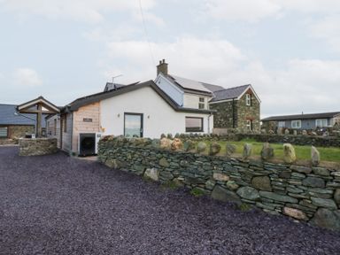 An exterior view of a house and stone wall at Hen Penmynydd Llanfwrog near Llanfachraeth
