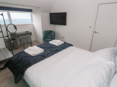 A bedroom with a bed, desk, mirror, and television at Shearwater in Praa Sands