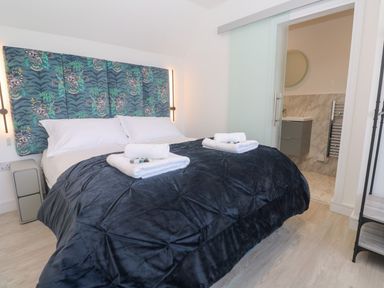 A bedroom with a bed and bathroom access at Shearwater in Praa Sands
