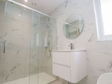 A bathroom with a shower, sink, and mirror at Shearwater in Praa Sands