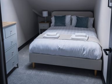 A bedroom with a bed, nightstand, dresser, and lamp at Green Bank in Betws-Y-Coed