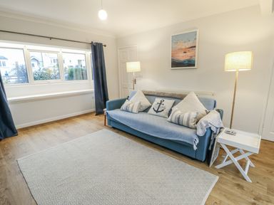 A living room with a sofa and lamp at 16 Ffordd Meigan in Beaumaris